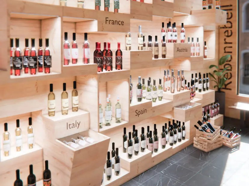 Innenansicht eines Weinfachhandels mit beleuchteten Weinflaschen im Regal.